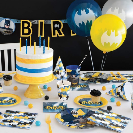 Batman-themed birthday party setup with cake, balloons, and tableware.
