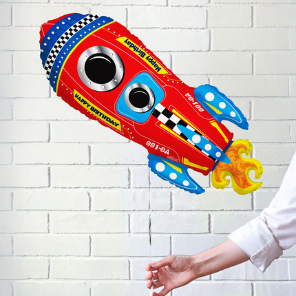 Colorful rocket-shaped balloon against a white brick wall