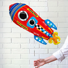 Colorful rocket-shaped balloon against a white brick wall