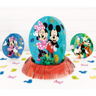 Disney-themed party decoration set featuring a large central oval table center with Minnie and Mickey Mouse on a turquoise background, surrounded by a red fringe base. Smaller matching round centerpieces for tables are arranged on both sides, with colorful Mickey-shaped confetti scattered on a white surface against a white paneled backdrop.