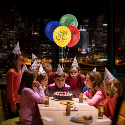 Children celebrating a birthday with balloons and a cake in an urban setting at night.