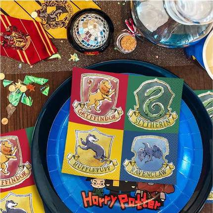 Harry Potter-themed party supplies including plates with house crests and a cake.