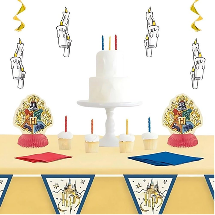 Decorative table setup with a cake, candles, and themed decorations on a yellow tablecloth.