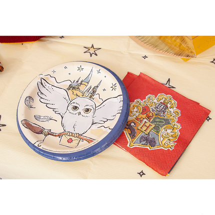 Children's plate with owl design and Hogwarts crest on a tablecloth.