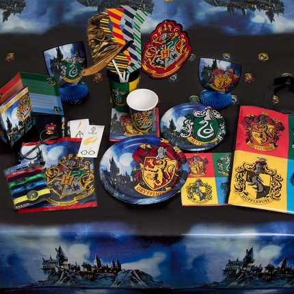 Collection of Harry Potter-themed merchandise including plates, cups, and books on a decorative surface with Hogwarts castle.