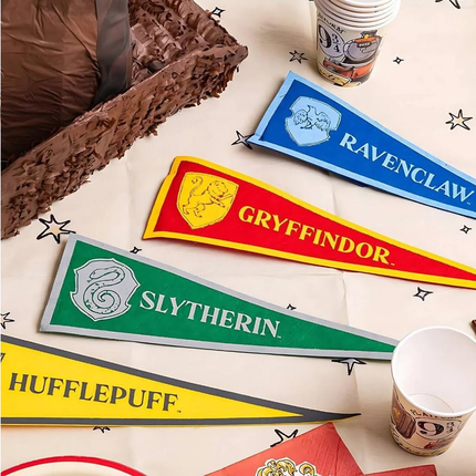 Four Hogwarts house pennants (Gryffindor, Slytherin, Hufflepuff, Ravenclaw) on a table.
