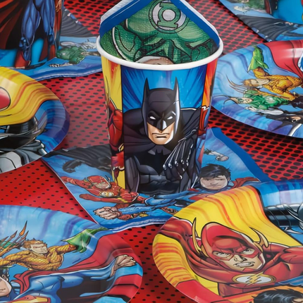 Superhero-themed cups and plates on a matching tablecloth.