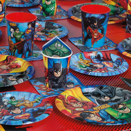Superhero-themed tableware including cups, plates, and napkins on a red checkered tablecloth.