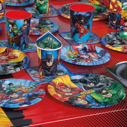 Superhero-themed tableware including plates, cups, and napkins on a red checkered tablecloth.