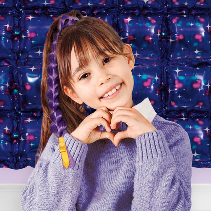A young girl with brown hair in a purple braided ponytail wearing a lavender knit sweater, posing with her hands together in front of a purple inflatable star-patterned wall. KPop Demon Hunters Character Braid Ponytail 1ct
