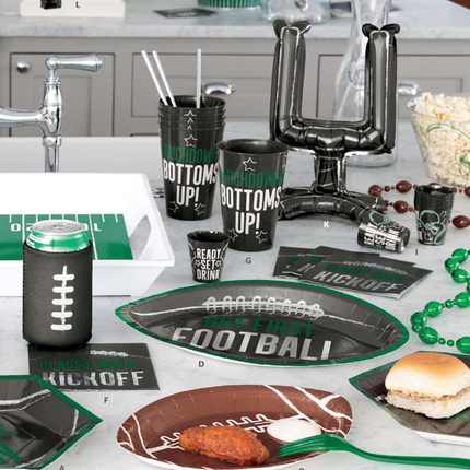 Football-themed party supplies including cups, plates, and decorations on a table.