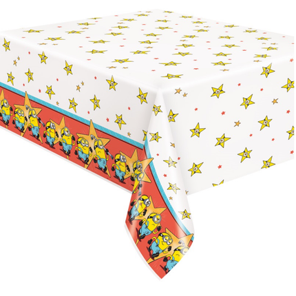 A rectangular party tablecloth featuring a white background with scattered yellow stars, small red dots, and a red border printed with cartoon minion characters.
