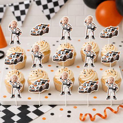 A set of baby racing-themed cupcake toppers displayed on cupcakes. The toppers feature cartoon-style baby racecar pilots in white and orange racing suits alongside colorful cartoon racecars.