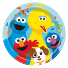 A round paper party plate featuring colorful Sesame Street characters including Big Bird, Cookie Monster, Elmo, Grover, and a small brown-and-white dog on a light blue background with confetti.