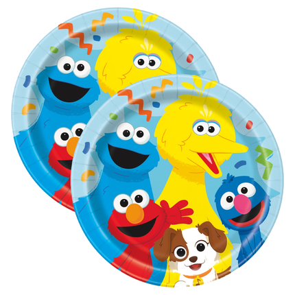 Two round paper plates featuring colorful Sesame Street character prints, including Big Bird, Cookie Monster, Elmo, Grover, and a small dog, on a plain white background.