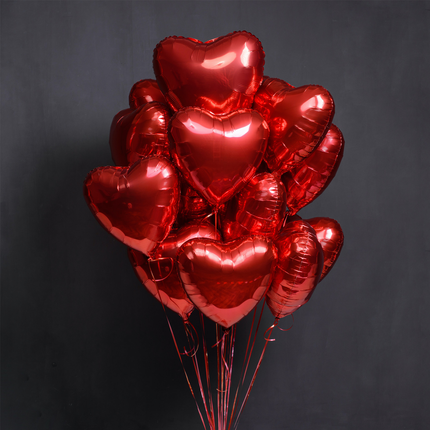 Bouquet of red heart-shaped balloons on a dark background